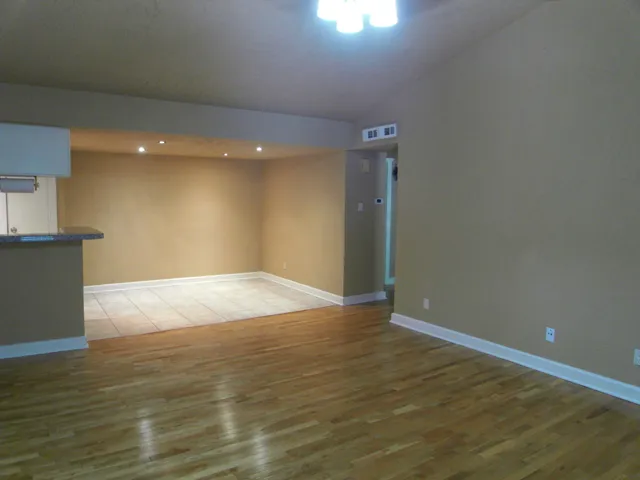 a view of a kitchen with kitchen island wooden floor and stainless steel appliances