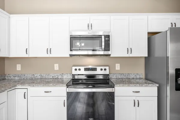 a kitchen with stainless steel appliances granite countertop a stove a microwave and a refrigerator