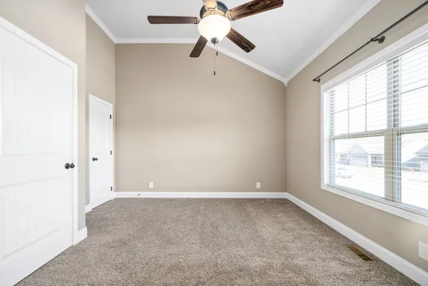 a view of an empty room with window and a chandelier fan