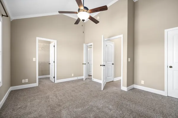 an empty room with closet and a ceiling fan