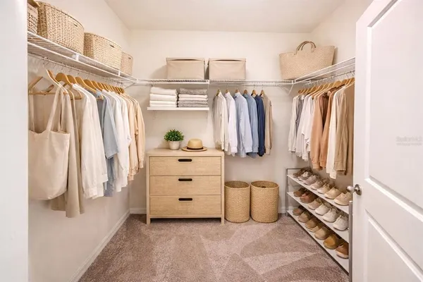 a view of walk in closet with clothes and shoes