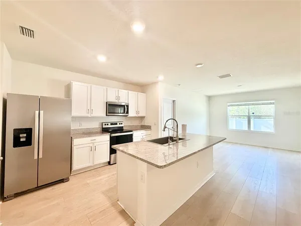 a kitchen with stainless steel appliances granite countertop a sink refrigerator and microwave