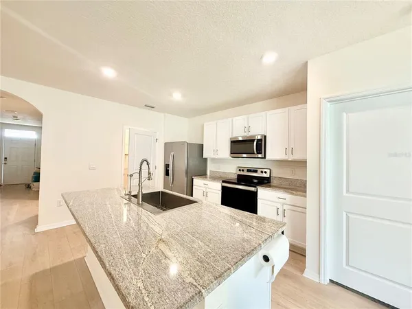 a kitchen with stainless steel appliances granite countertop a sink a stove and a refrigerator