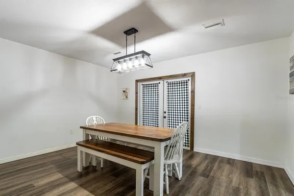 a view of a dining room with wooden floor a chandelier a wooden table and chairs