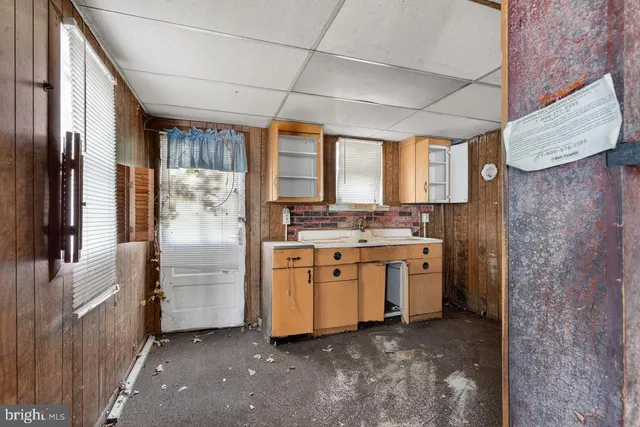 a view of a hallway with wooden floor and a bathroom