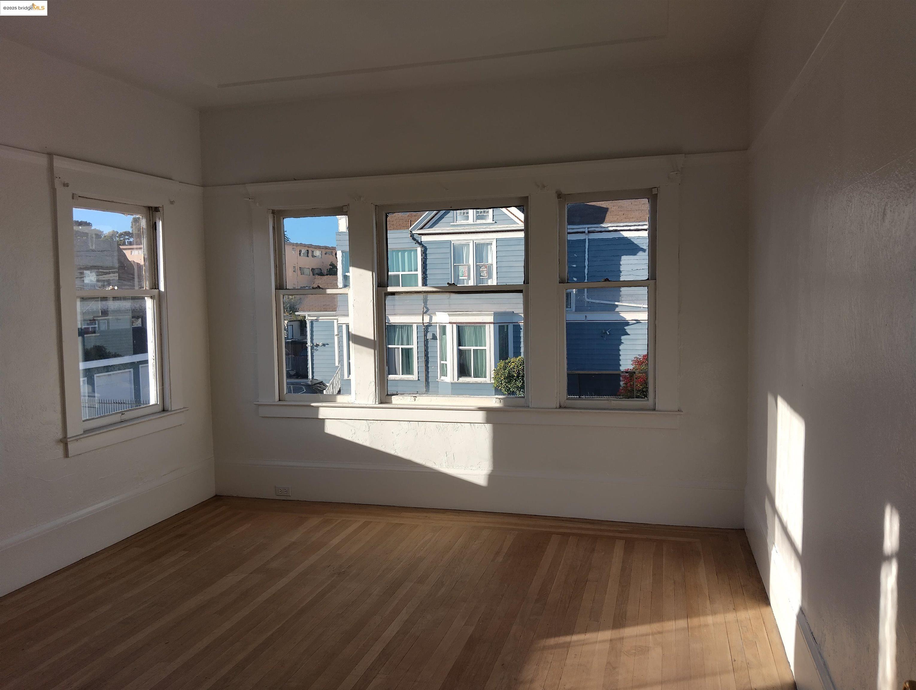 847 East 18th Street Oakland, CA 94606 - Photo 21 of 60 an empty room with wooden floor and windows