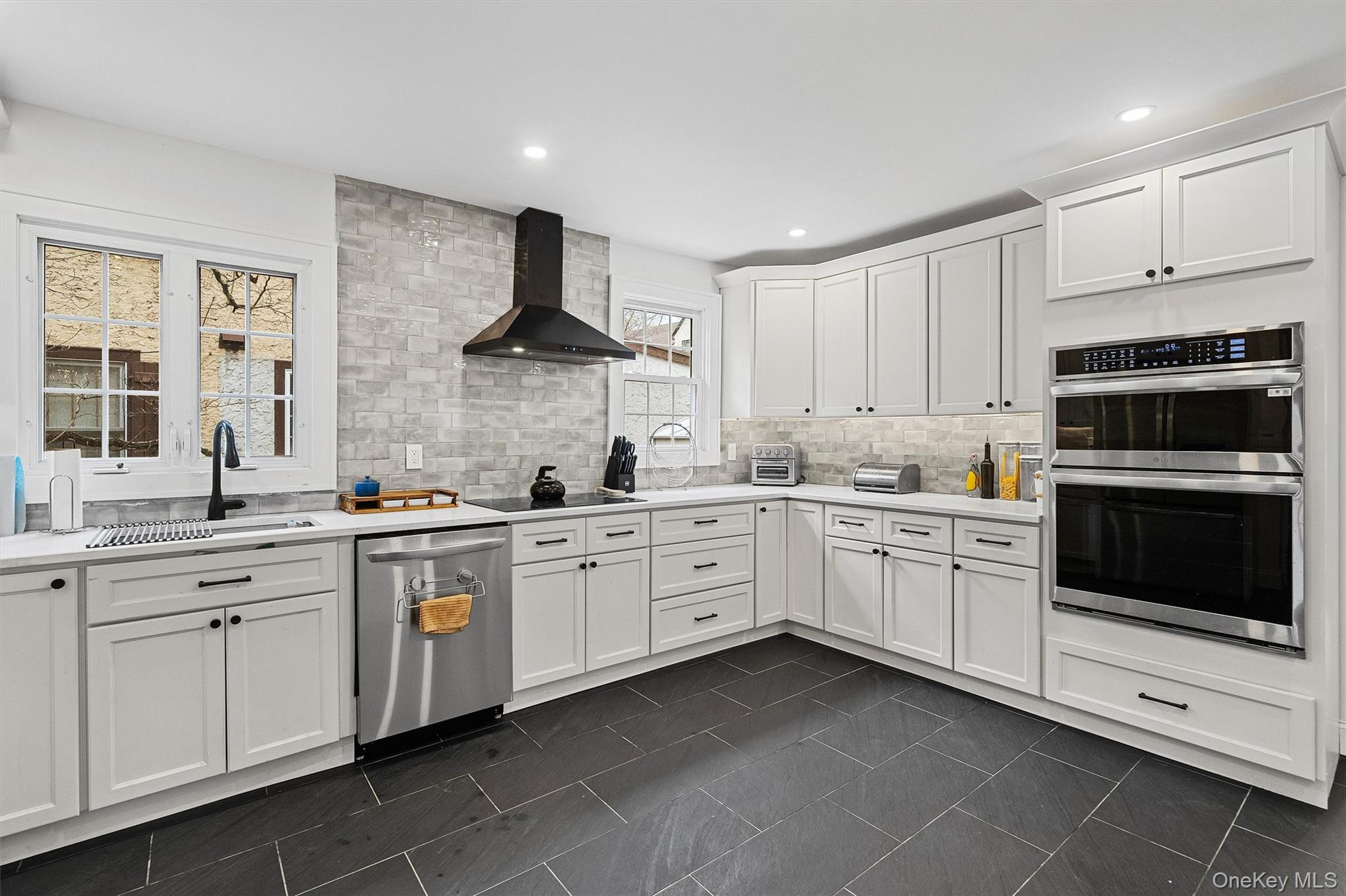 112 Ralph Avenue White Plains, NY 10606 - Photo 11 of 30 Kitchen with exhaust hood, a sink, light countertops, stainless steel appliances, and decorative backsplash
