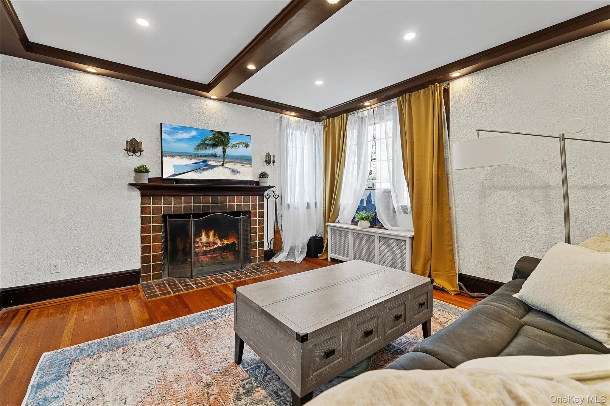 112 Ralph Avenue White Plains, NY 10606 - Photo 4 of 30 Living room featuring a textured wall, a tiled fireplace, radiator, and wood finished floors