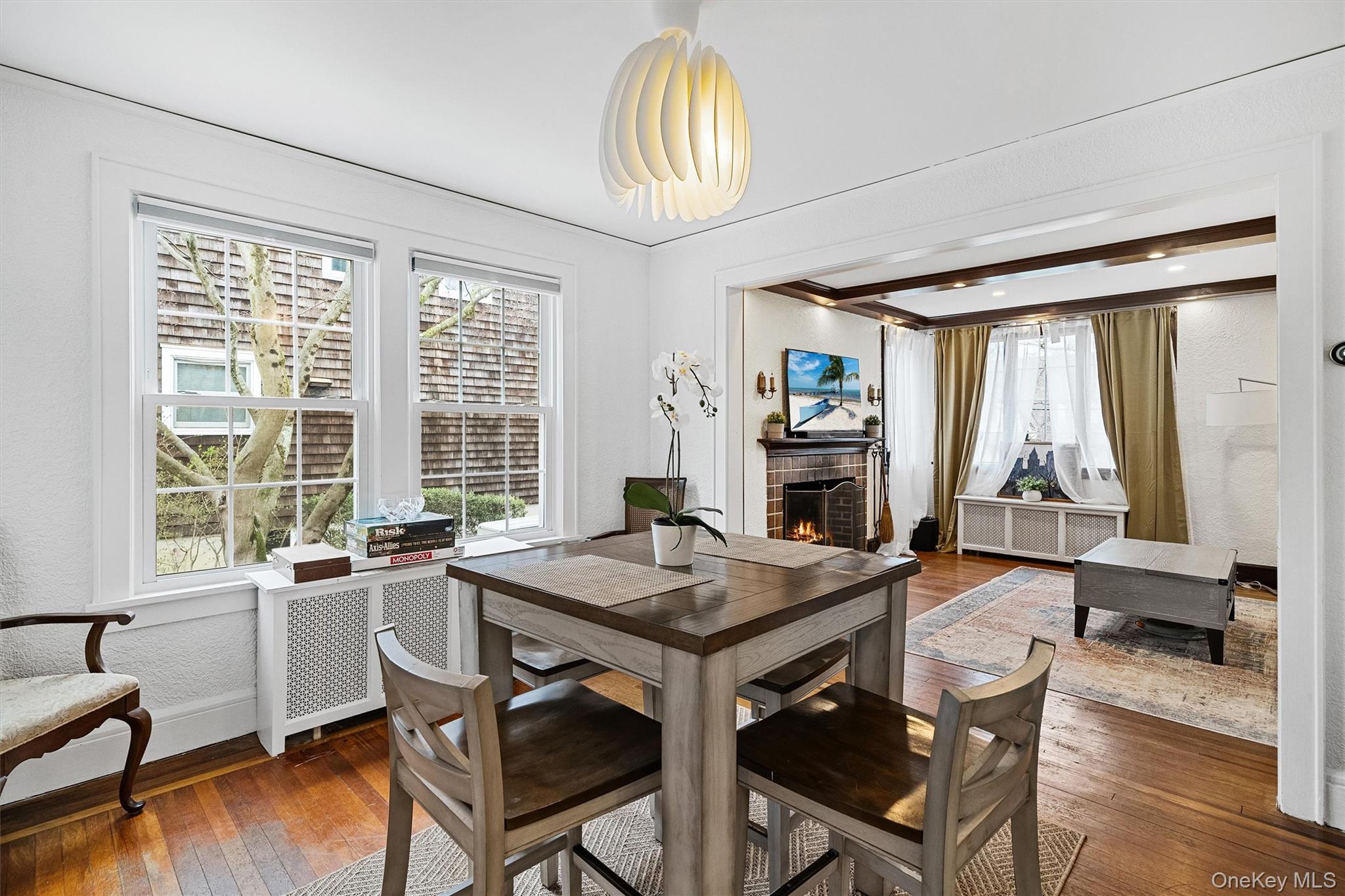 112 Ralph Avenue White Plains, NY 10606 - Photo 10 of 30 Dining room featuring dark wood-style flooring, baseboards, radiator, and a lit fireplace
