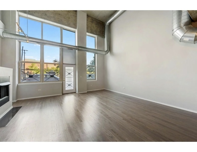 6 South Laflin Street, Unit 110S Chicago, IL 60607 - Photo 8 of 11 a view of an empty room with a window and wooden floor