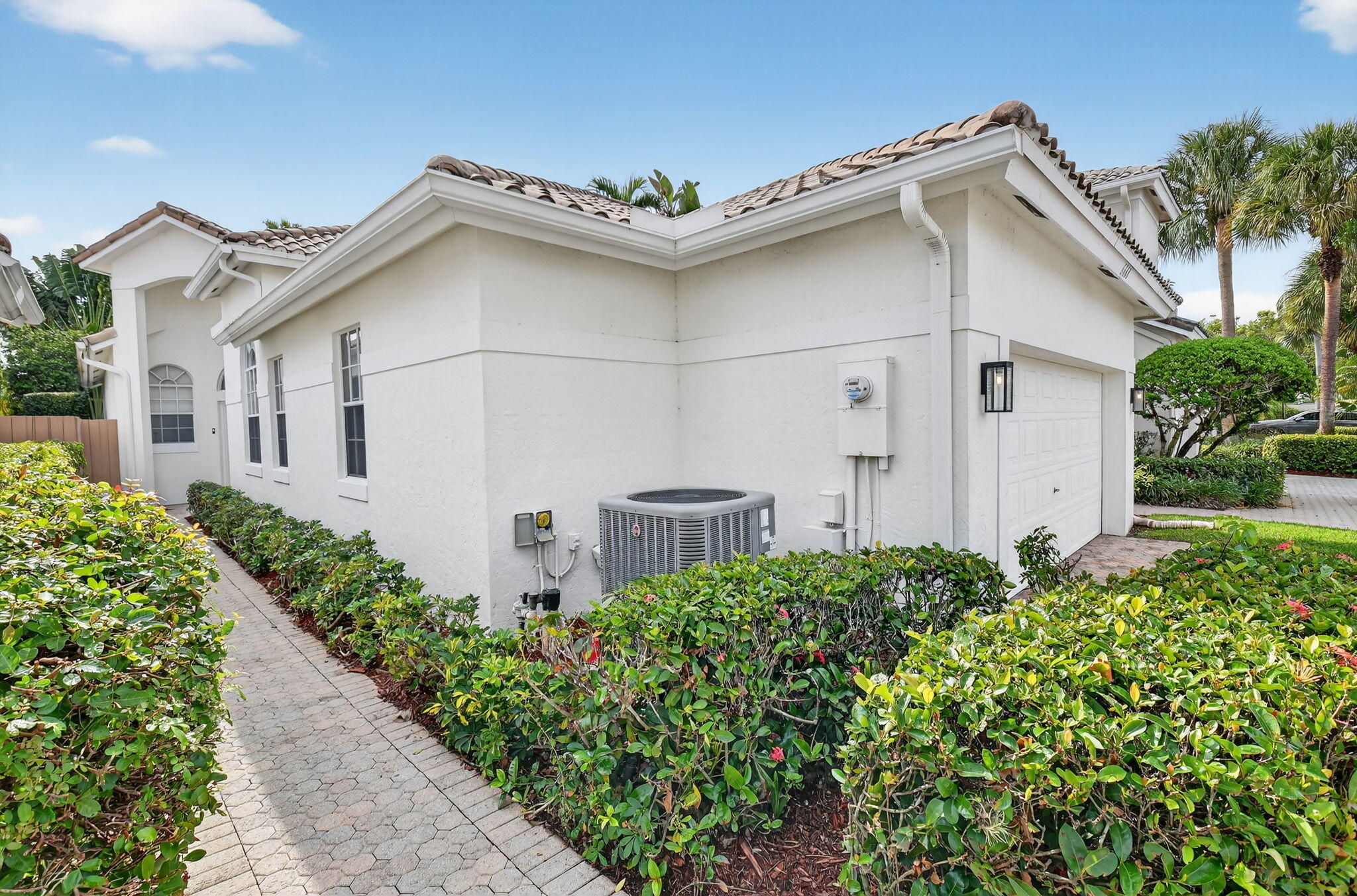 6668 Northwest 25th Terrace Boca Raton, FL 33496 - Photo 2 of 53 a white house with a small yard and flower plants