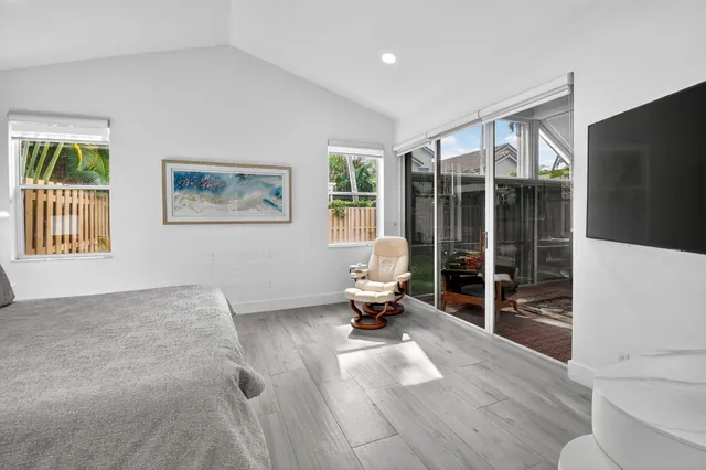 a living room with furniture a flat screen tv and a floor to ceiling window