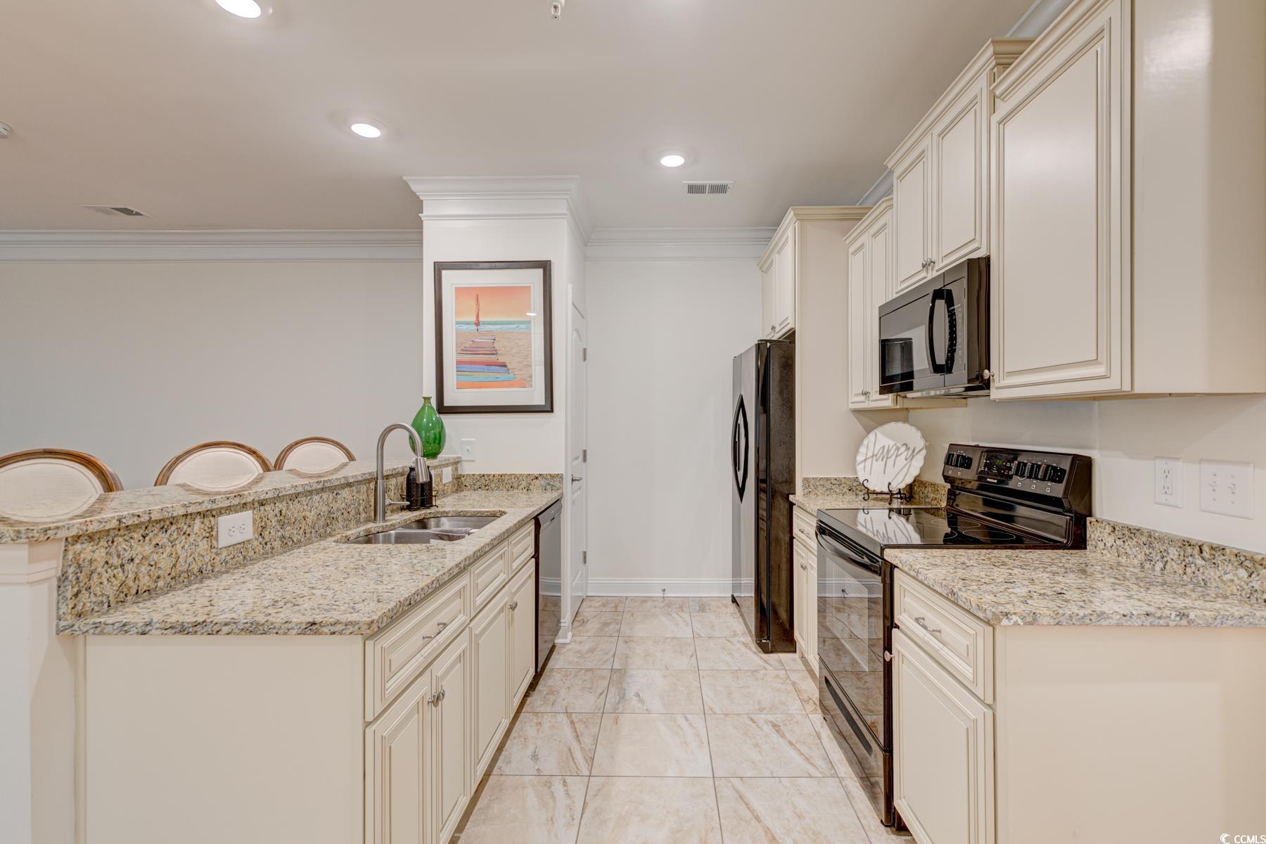 130 Puffin Drive, Unit 2B Pawleys Island, SC 29585 - Photo 11 of 34 Kitchen with black appliances, light stone countertops, a peninsula, crown molding, and recessed lighting