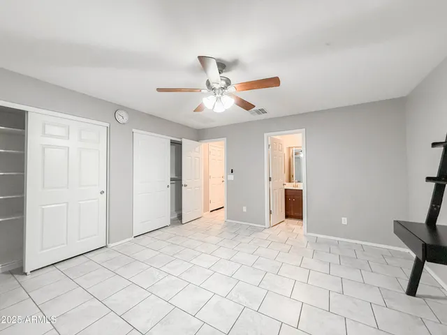 a view of an empty room with window and chandelier fan