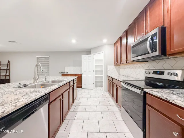 a large kitchen with stainless steel appliances granite countertop a sink stove and cabinets