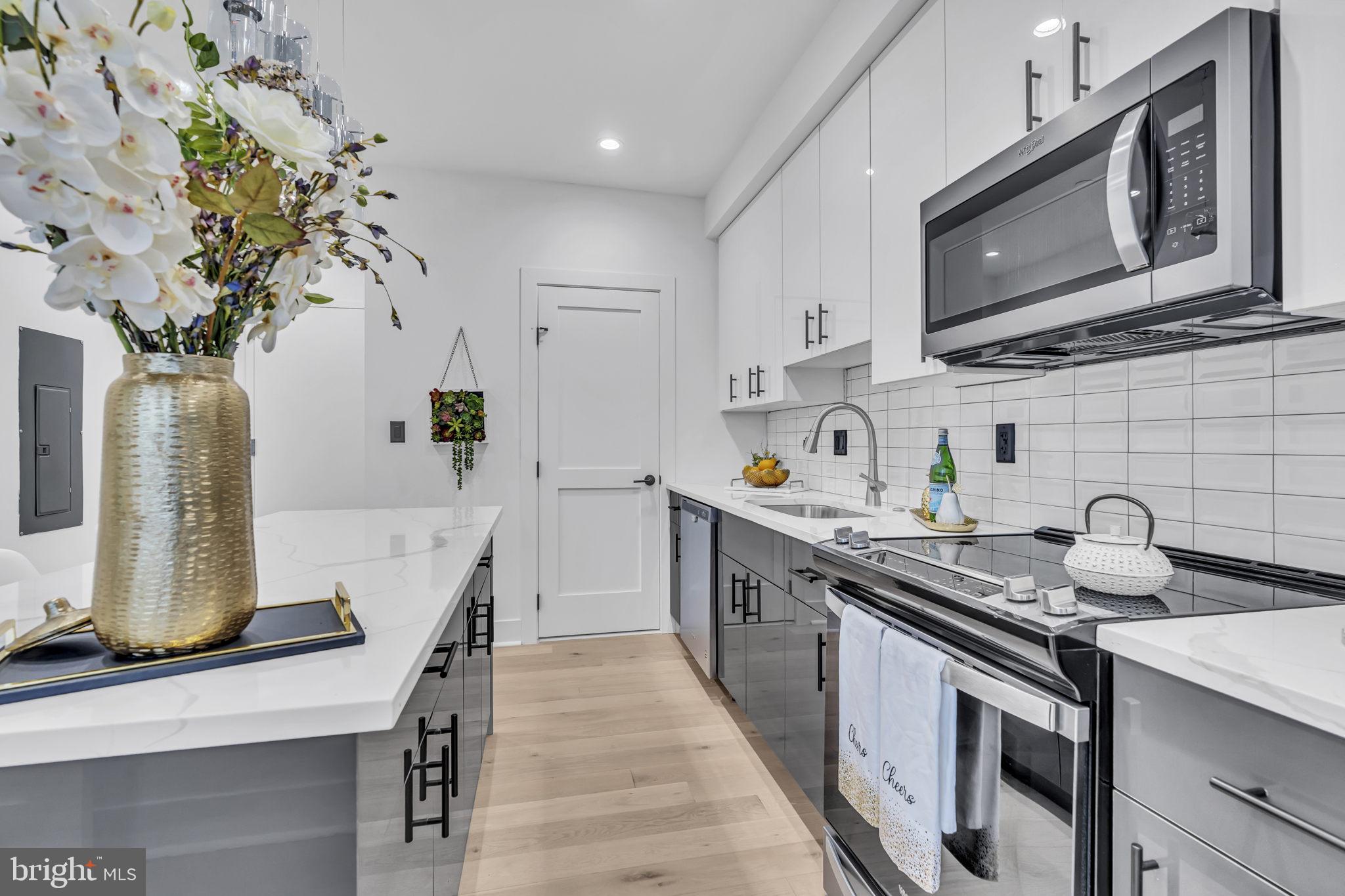 1103 Fern Street Northwest, Unit 301 Washington, DC 20012 - Photo 26 of 57 a kitchen with stainless steel appliances granite countertop a sink a stove a microwave a sink and cabinets