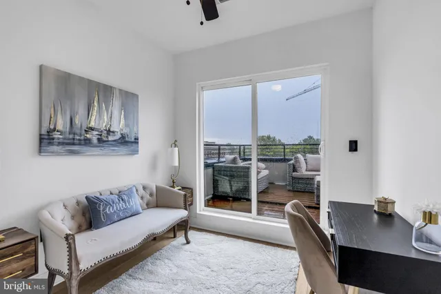 a living room with stainless steel appliances furniture wooden floor and a large window