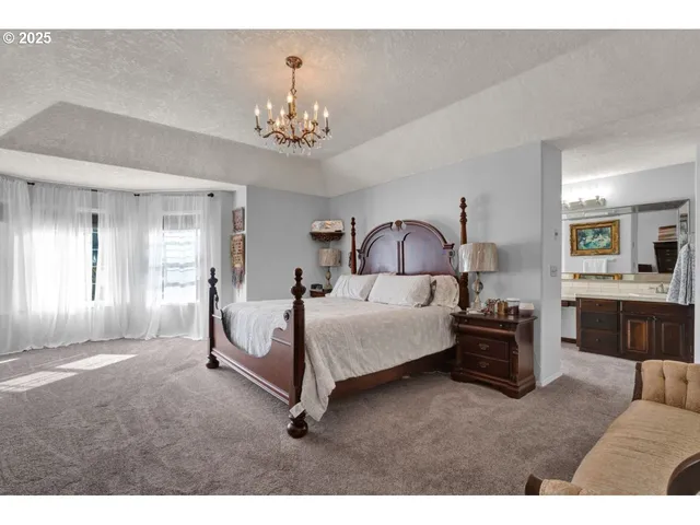 a spacious bedroom with a bed and a chandelier