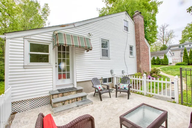 a view of a patio with couches table and chairs and wooden fence
