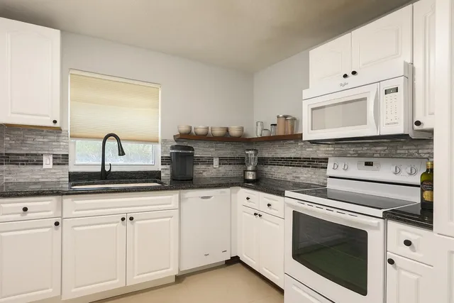 a kitchen with granite countertop white cabinets and white appliances
