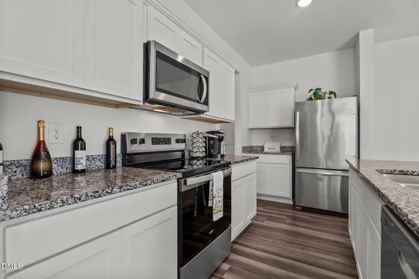 a kitchen with granite countertop a sink a counter top space and cabinets