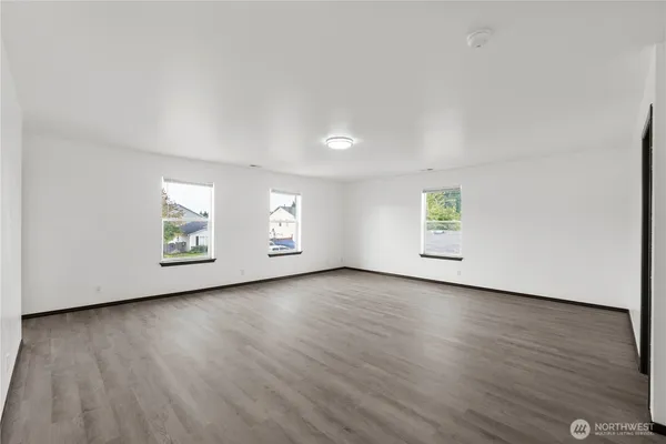 an empty room with wooden floor and window