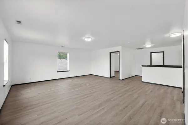 an empty room with wooden floor and a kitchen