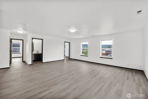 an empty room with wooden floor and windows