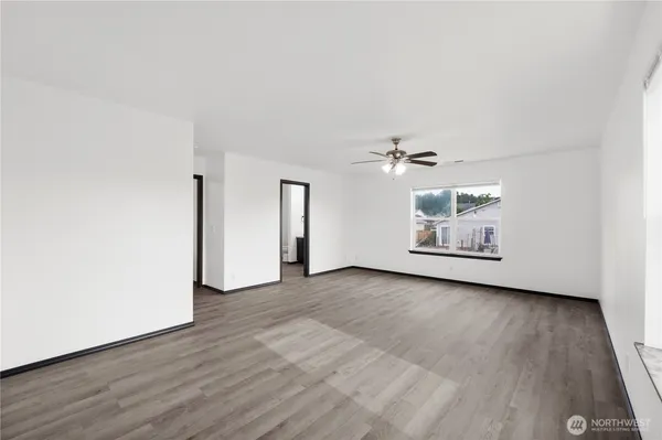an empty room with wooden floor ceiling fan and window