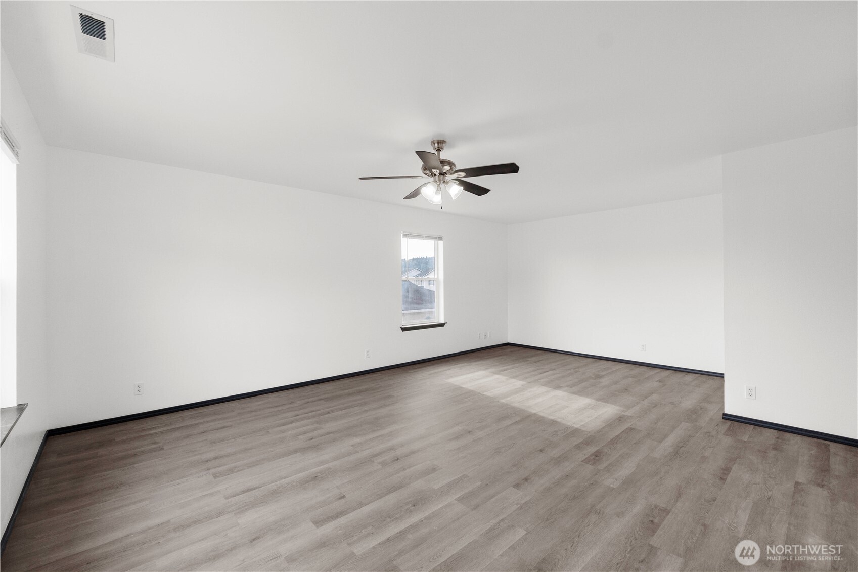 116 Mazza Street Northeast Orting, WA 98360 - Photo 24 of 39 an empty room with wooden floor chandelier fan and windows