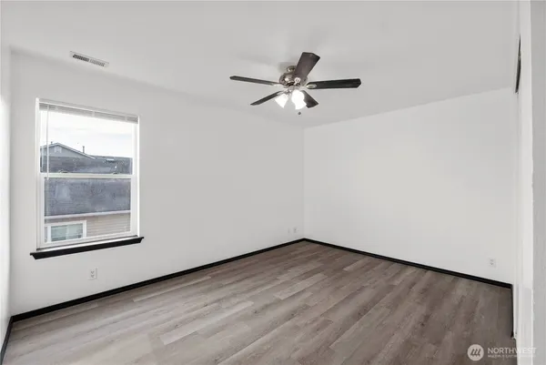 a view of an empty room with a window and wooden floor