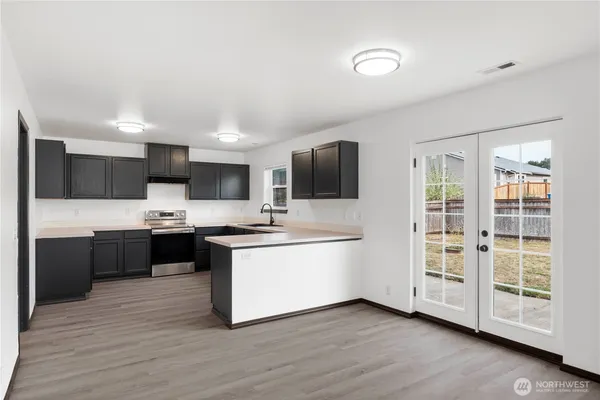 a kitchen with stainless steel appliances white cabinets a sink a stove a refrigerator and a microwave oven