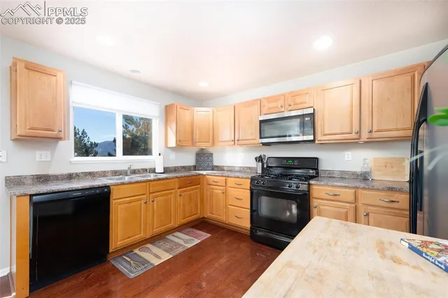 a kitchen with stainless steel appliances granite countertop wooden cabinets a stove a sink and a microwave
