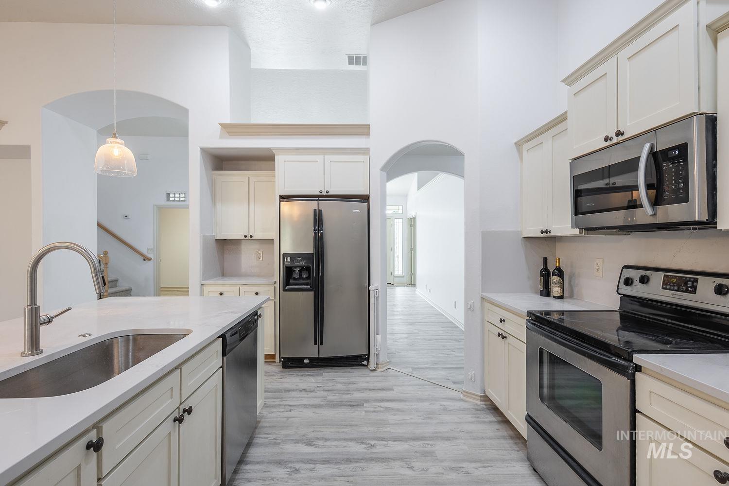 4227 North Rhodes Avenue Meridian, ID 83646 - Photo 11 of 42 Kitchen with stainless steel appliances, arched walkways, pendant lighting, light stone countertops, and a high ceiling