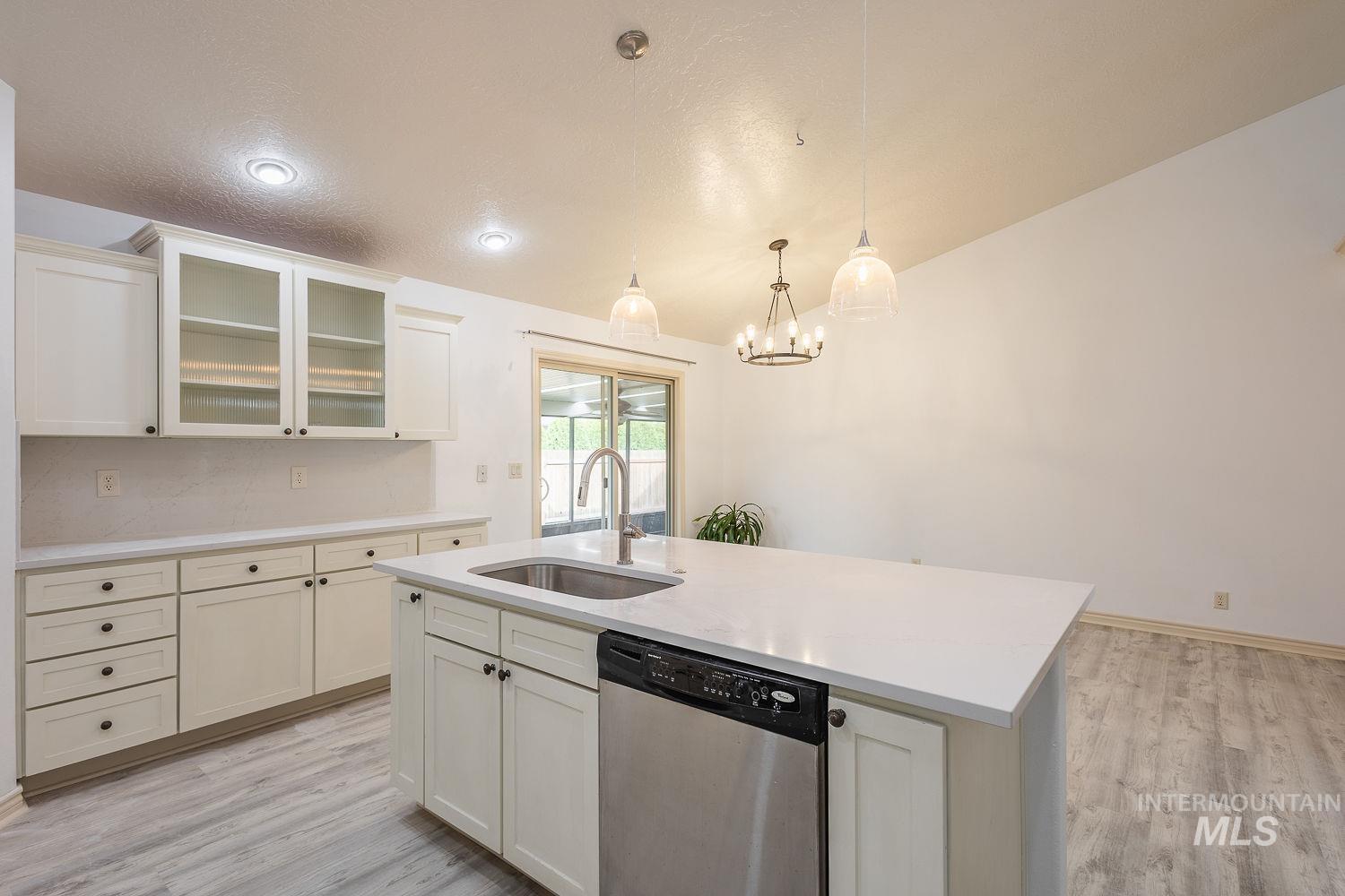 4227 North Rhodes Avenue Meridian, ID 83646 - Photo 12 of 42 Kitchen with dishwasher, glass fronted cabinets, an island with sink, and light wood-style floors