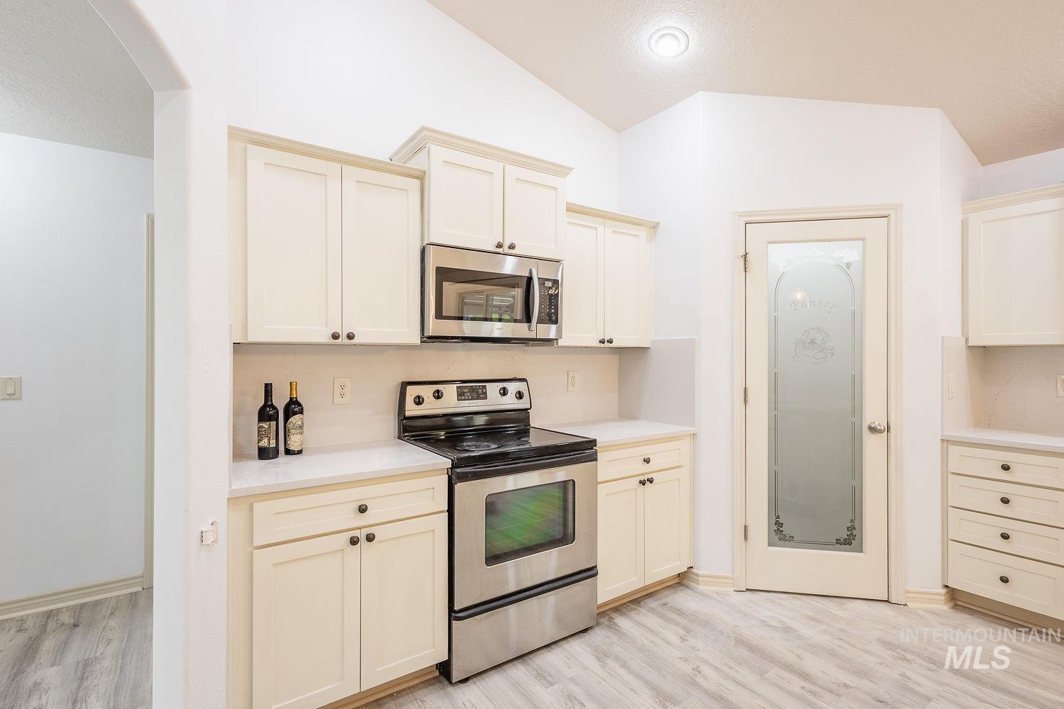 4227 North Rhodes Avenue Meridian, ID 83646 - Photo 14 of 42 Kitchen featuring stainless steel appliances, light wood finished floors, cream cabinets, and vaulted ceiling