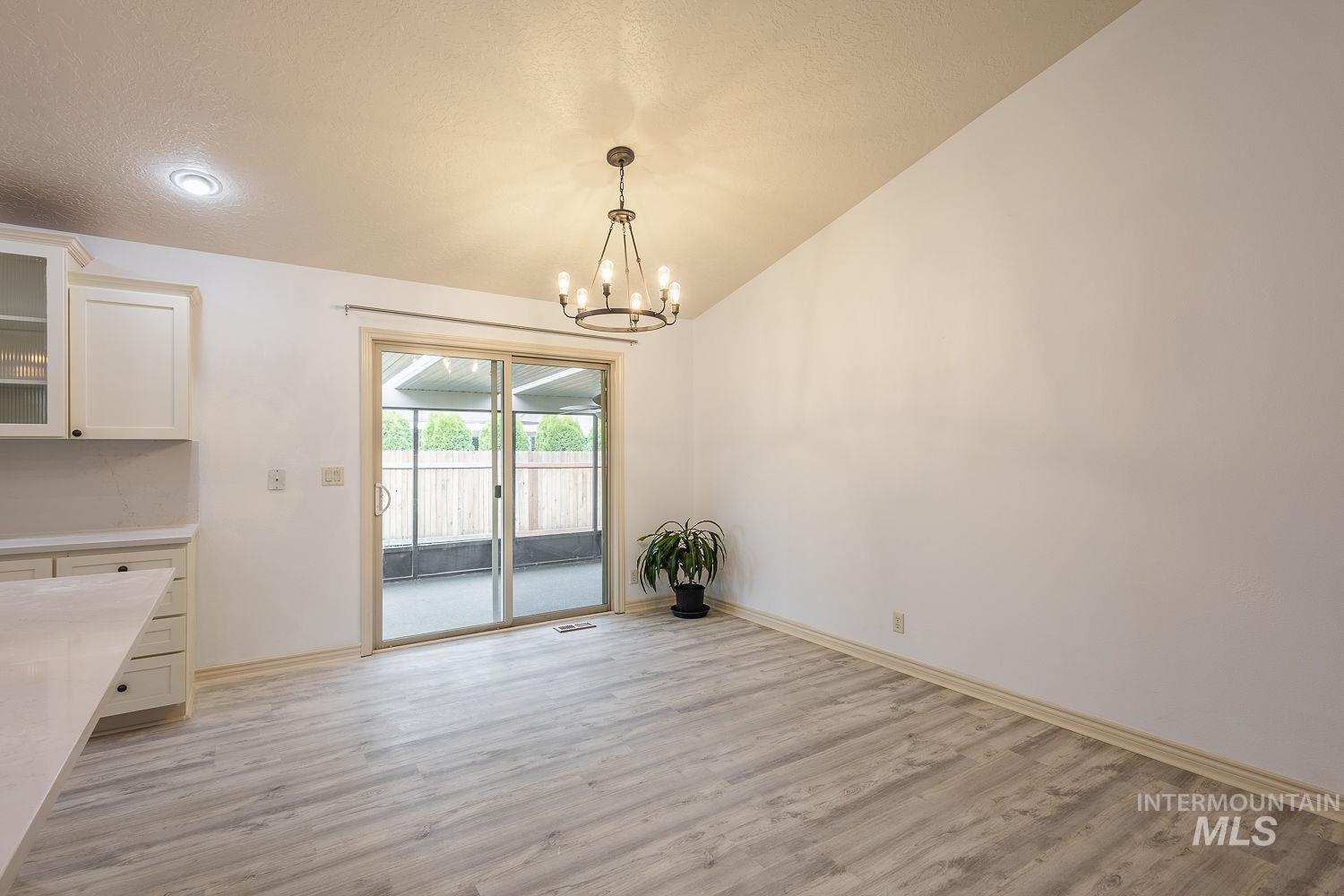 4227 North Rhodes Avenue Meridian, ID 83646 - Photo 15 of 42 Unfurnished dining area with light wood finished floors and a chandelier