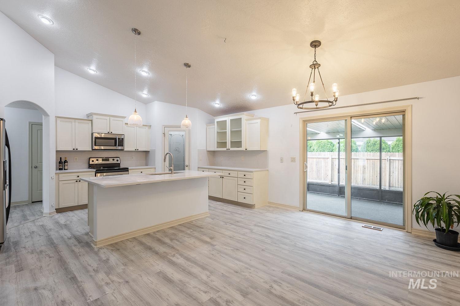 4227 North Rhodes Avenue Meridian, ID 83646 - Photo 16 of 42 Kitchen with glass fronted cabinets, stainless steel appliances, arched walkways, an island with sink, and vaulted ceiling