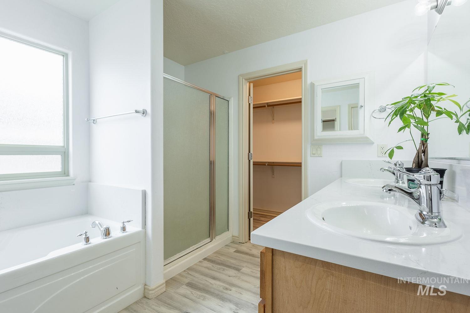 4227 North Rhodes Avenue Meridian, ID 83646 - Photo 20 of 42 Bathroom with a bath, double vanity, a walk in closet, light wood finished floors, and a stall shower