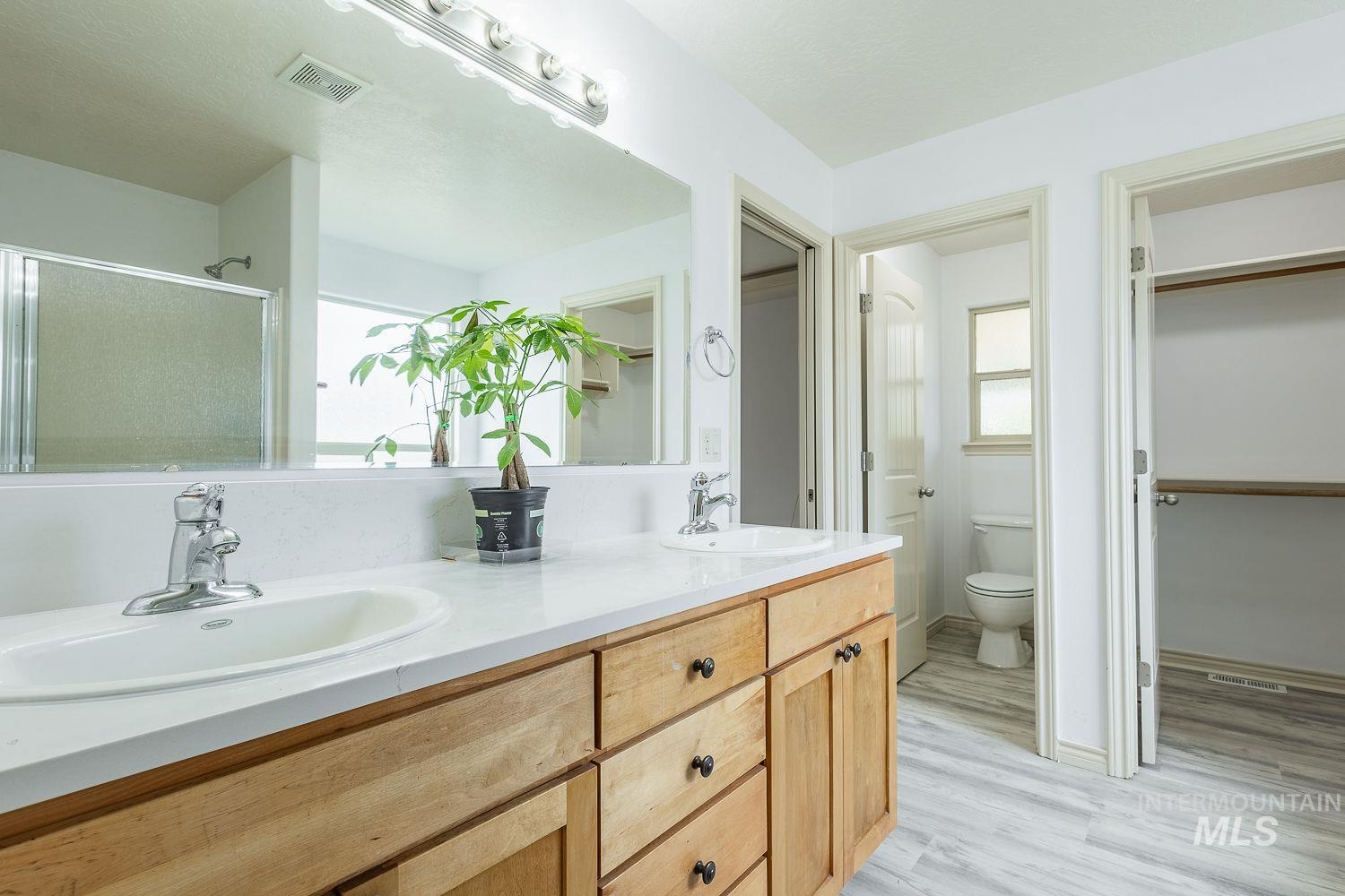 4227 North Rhodes Avenue Meridian, ID 83646 - Photo 21 of 42 Bathroom with double vanity, a spacious closet, a stall shower, and light wood finished floors