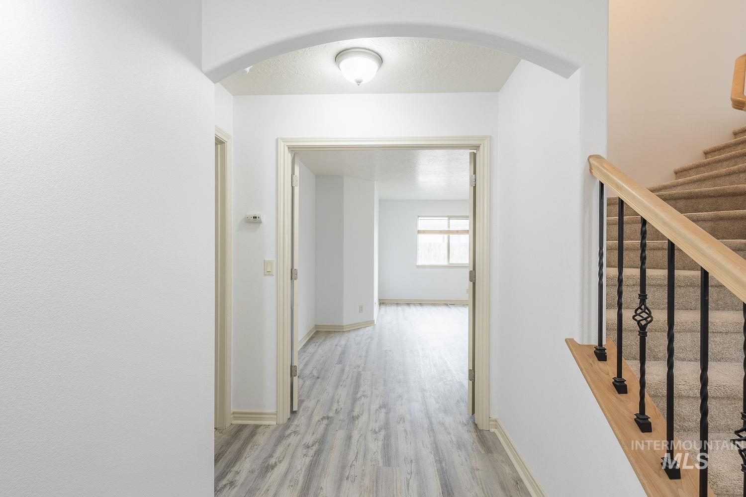 4227 North Rhodes Avenue Meridian, ID 83646 - Photo 24 of 42 Corridor featuring arched walkways, light wood finished floors, and a textured ceiling
