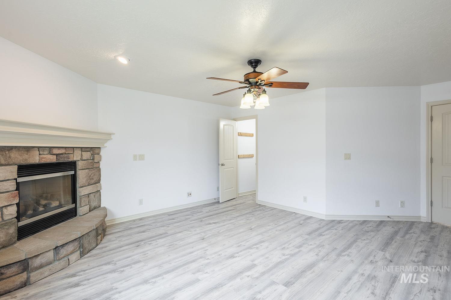 4227 North Rhodes Avenue Meridian, ID 83646 - Photo 26 of 42 Unfurnished living room with ceiling fan, a fireplace, and light wood-type flooring
