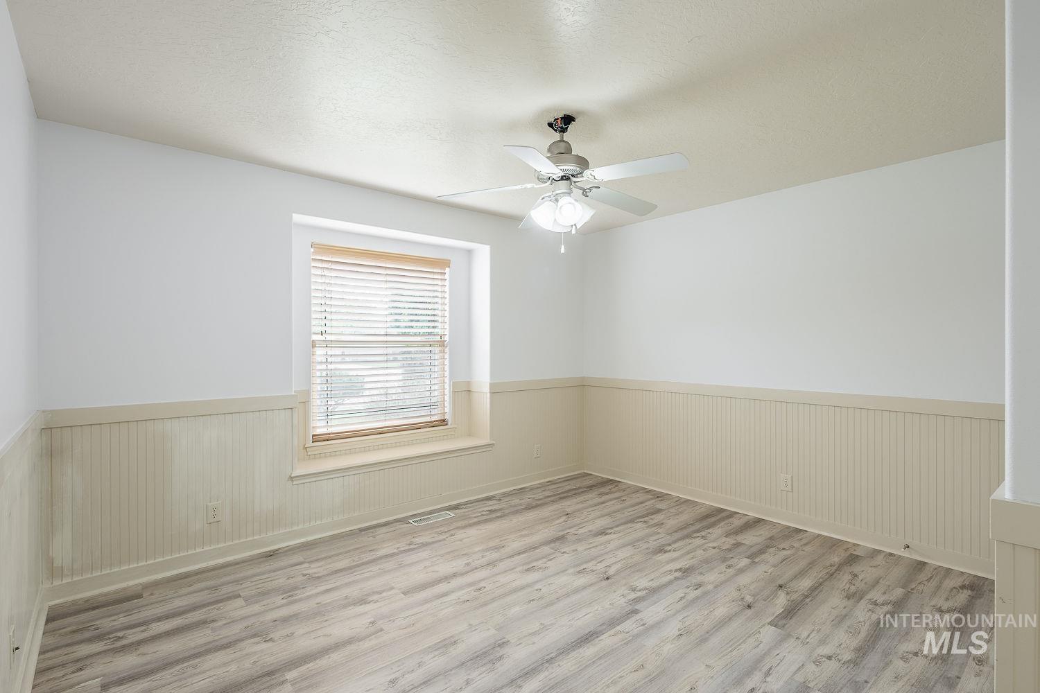 4227 North Rhodes Avenue Meridian, ID 83646 - Photo 27 of 42 Spare room with wainscoting, light wood finished floors, ceiling fan, a textured ceiling, and wooden walls