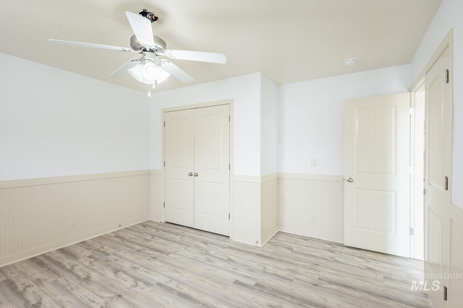 4227 North Rhodes Avenue Meridian, ID 83646 - Photo 28 of 42 Unfurnished bedroom with light wood-type flooring, a wainscoted wall, ceiling fan, and a closet