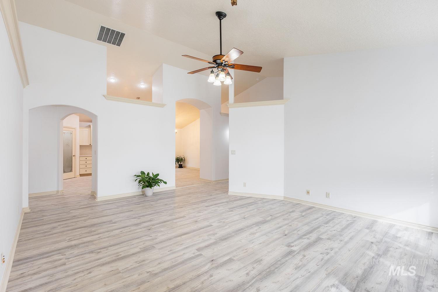 4227 North Rhodes Avenue Meridian, ID 83646 - Photo 4 of 42 Unfurnished living room featuring a ceiling fan, light wood-type flooring, arched walkways, and lofted ceiling