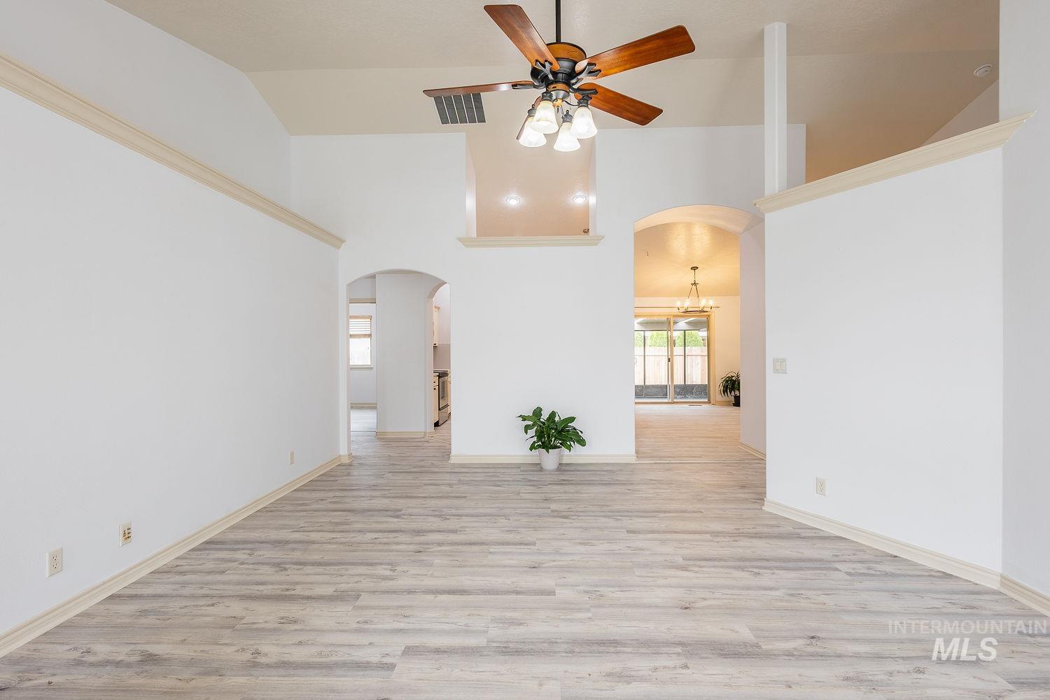 4227 North Rhodes Avenue Meridian, ID 83646 - Photo 6 of 42 Unfurnished room with arched walkways, ceiling fan, light wood-style floors, and lofted ceiling