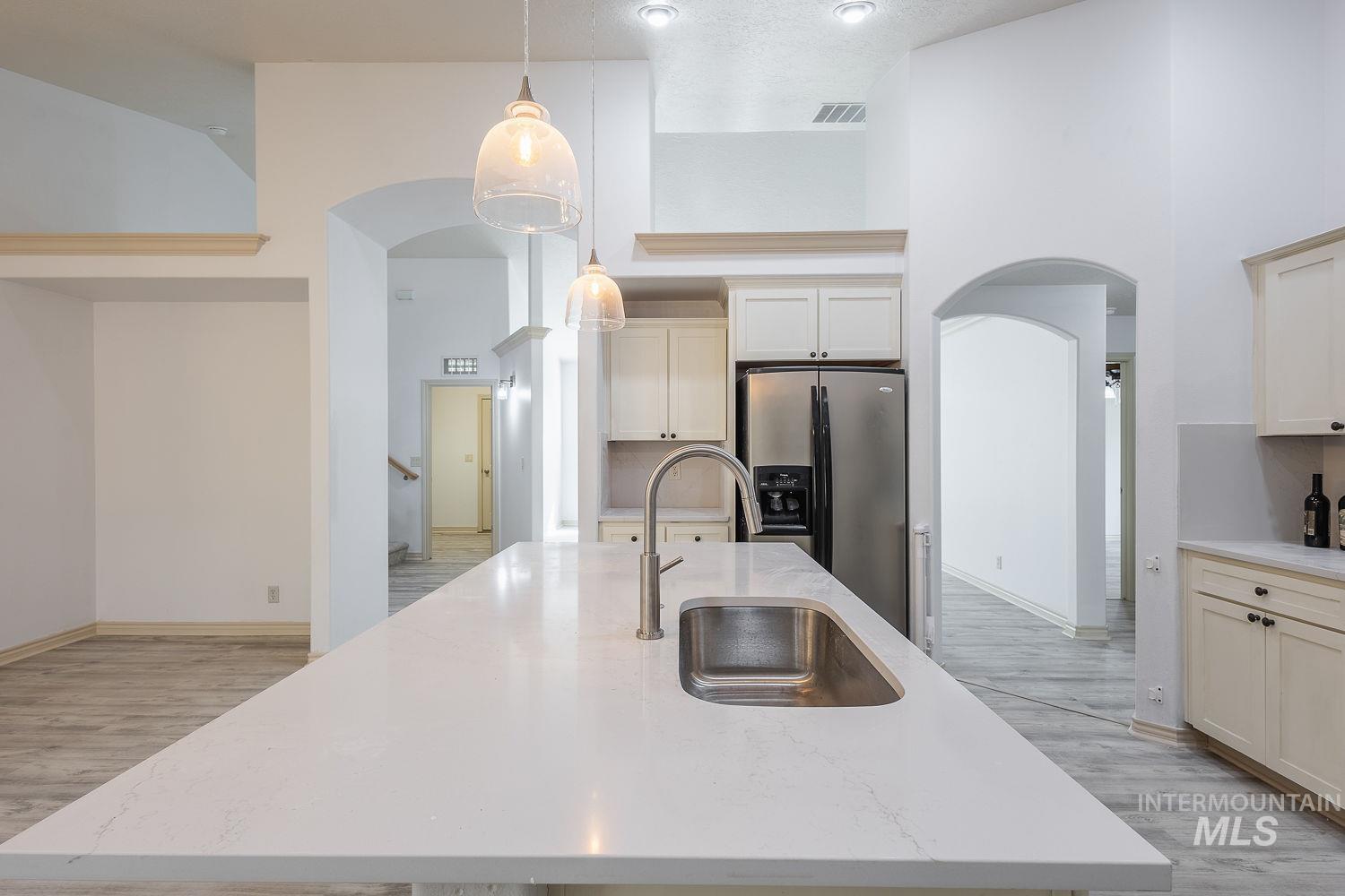 4227 North Rhodes Avenue Meridian, ID 83646 - Photo 10 of 42 Kitchen with arched walkways, a high ceiling, an island with sink, stainless steel fridge with ice dispenser, and pendant lighting