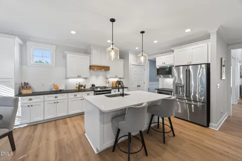 a kitchen with stainless steel appliances a refrigerator a sink dishwasher a stove and white countertops with wooden floor