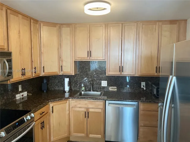a kitchen with stainless steel appliances granite countertop a refrigerator sink and cabinets