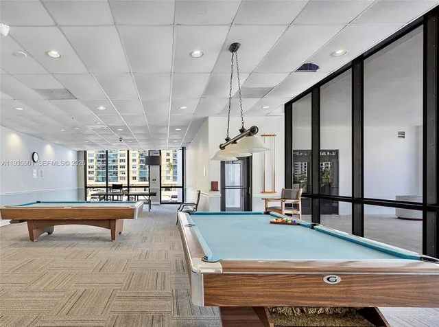 a large room with pool table and windows